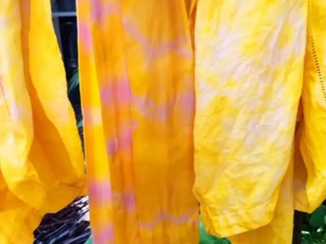 yellow and pink naturally tie-dyed scarves and napkins hanging outside