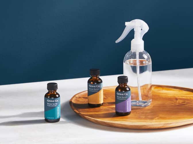 Essential oil bottles sitting next to a spray bottle on a counter with a wooden tray underneath