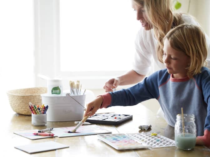 blonde mom and child doing watercolor painting at dining table