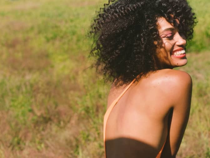 Black woman smiling outdoors in a sunny field