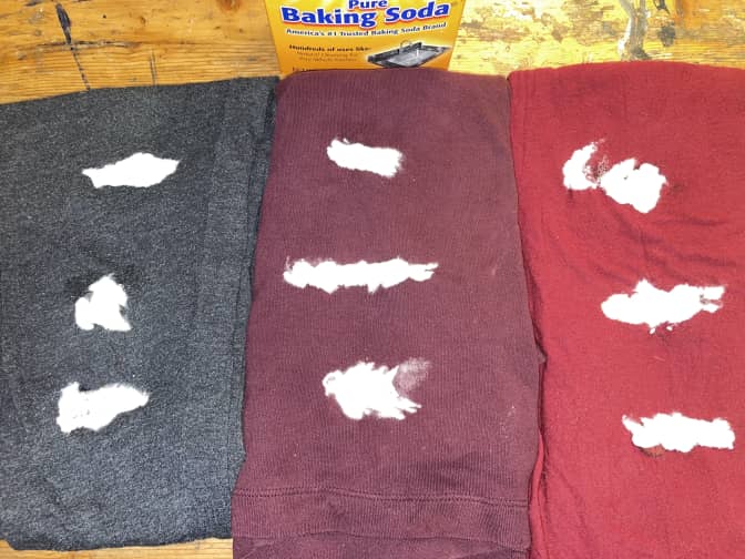 Three pieces of clothing with chapstick stains being treated with baking soda.