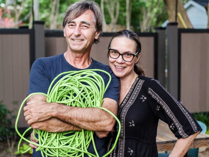 Image of Al and Suzy Newsom holding green garden hose outside