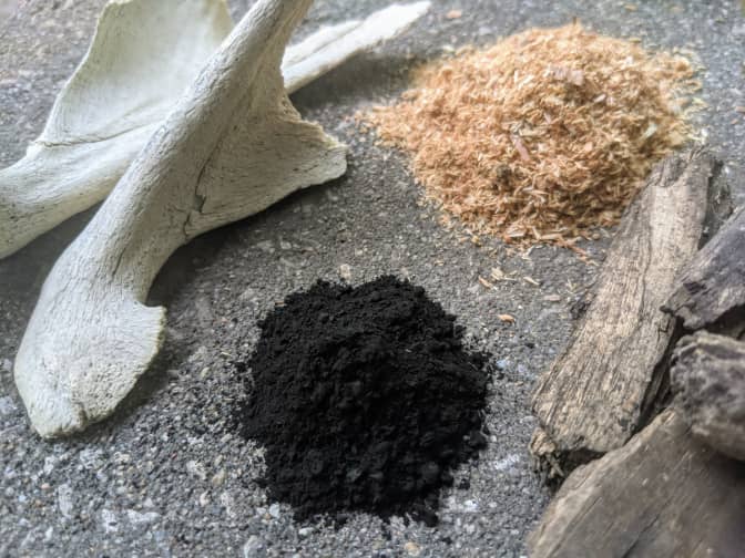 Photo of pile of charcoal and sawdust with pieces of wood