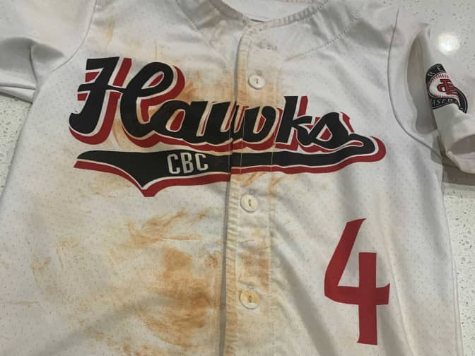 Image of white baseball jersey with dirt and grass stains down the middle front
