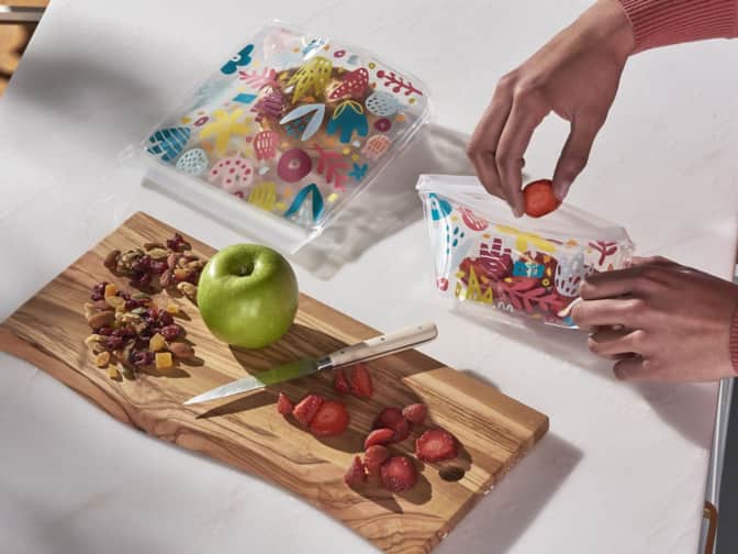 Reusable food storage bags with apple and nuts on cutting board