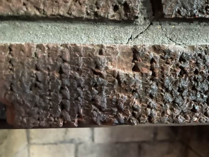 a closeup of a dirty, sooty brick in a brick fireplace