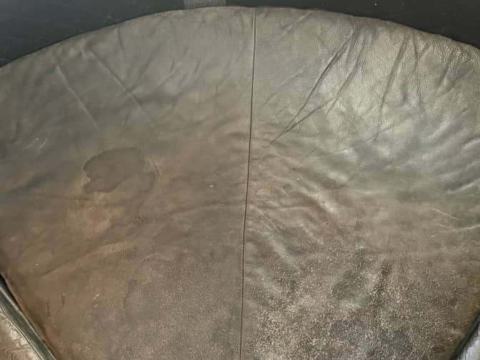 A leather couch with a slightly less noticeable stain after it's been scrubbed.