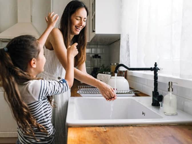mother and daughter playing by sink in kitchen