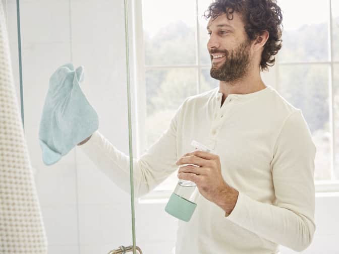 man cleaning with microfiber cloth and spray bottle