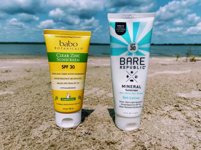 Photo of two sunscreen bottles next to each other on a beach