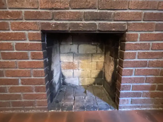 a dirty brick fireplace about to be cleaned