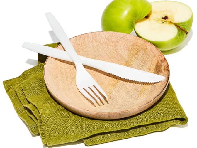 Illustration of a compostable knife and a fork on a plate next to an apple. 