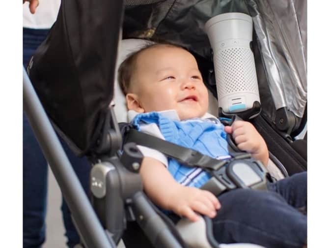 Image of a baby in a stroller with portable air purifier next to them