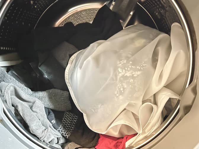 a Guppyfriend mesh laundry bag in the washing machine with other clothes