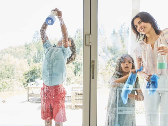 Family using spray cleaner and towels to wipe down and clean glass doors