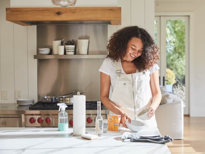 woman smiling in kitchen mixing ingredients for baking soda cleaning paste