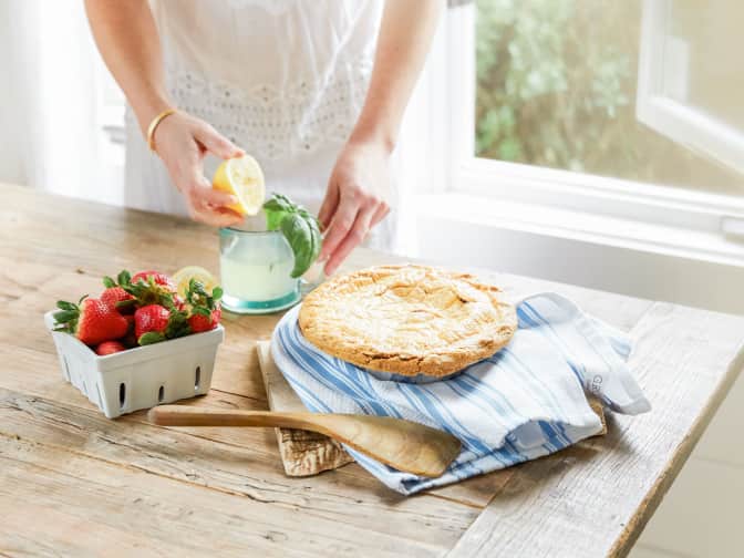 Imageof a pie, strawberries and lemonade on a table next to a women