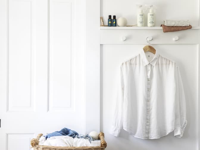 Photo of white shirt hanging up next to laundry basket