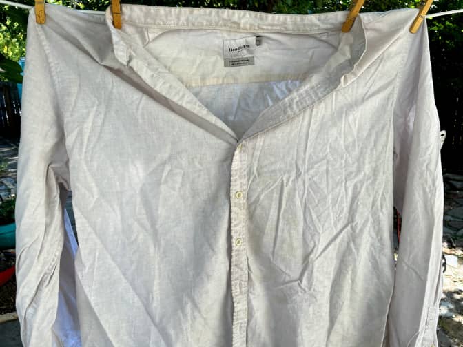 Photo of dirty white linen and cotton shirt hanging on clothesline