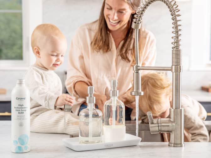 Young adult cleans the brass sink with two young children helping