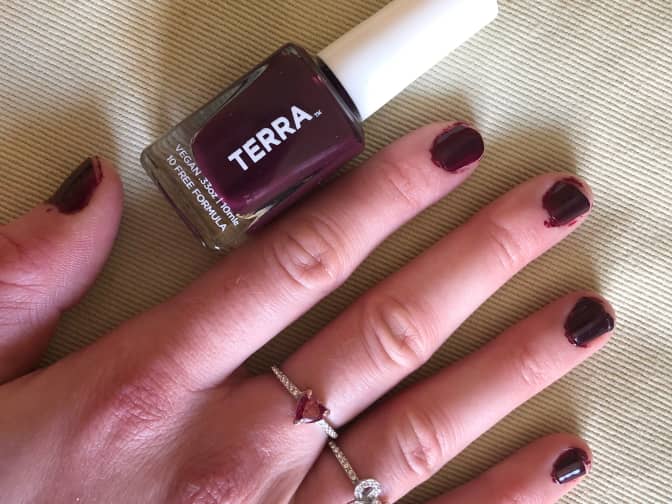a hand with freshly painted fingernails next to a bottle of Terra nail polish