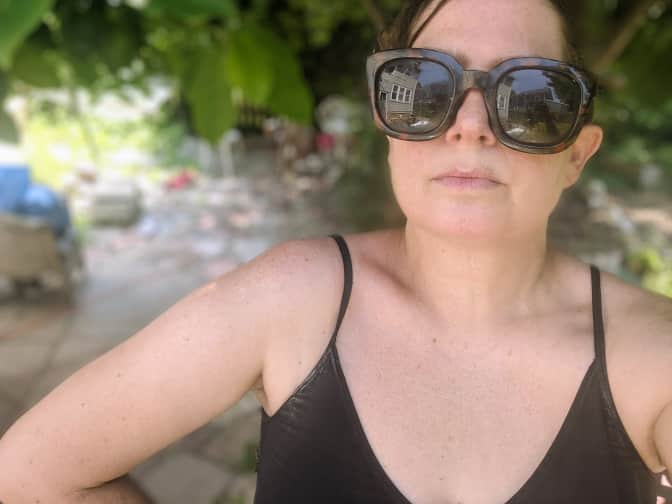 Photo of woman wearing sunglasses and black sleeveless top outside