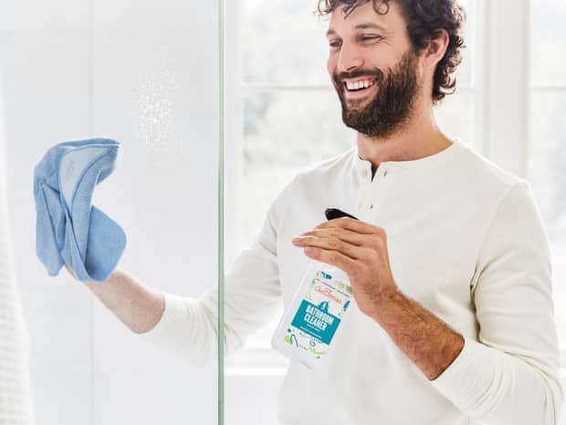 Man cleaning his shower door with Aunt Fannie's bathroom cleaner