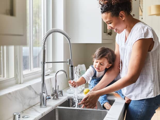 mom and child washing hands at kitchen sink
