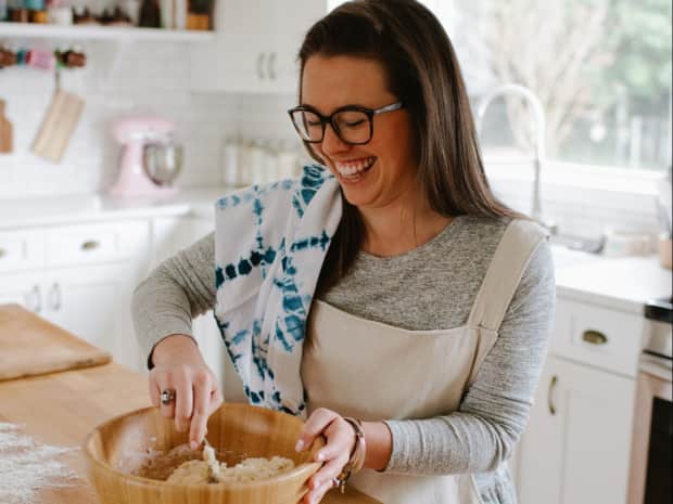 woman mixing food in mixing bowl on top of butcher block countertop