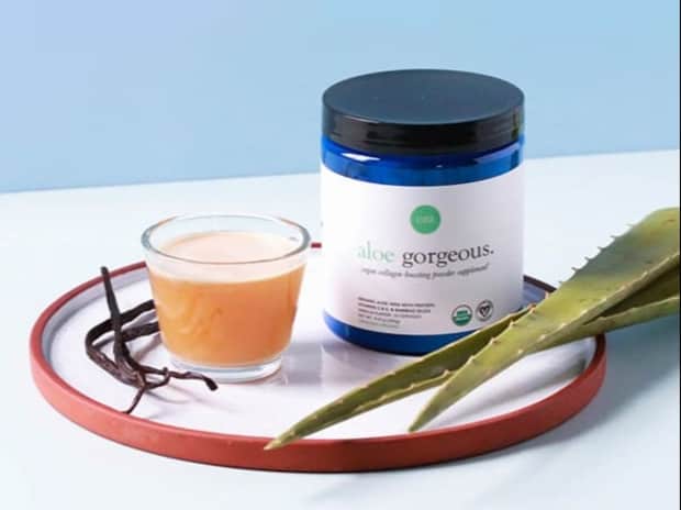 Ora Organic’s Aloe Gorgeous Vegan Collagen Booster on a plate with a cup of tea and some aloe vera