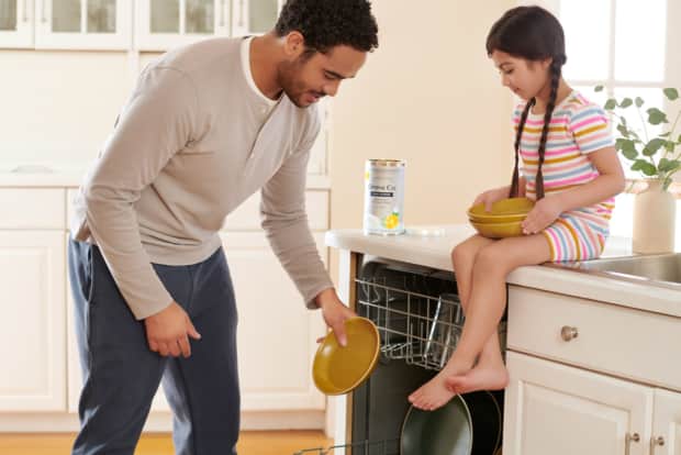a man and little girl in the kitchen emptying the clean dishes from the dishwasher