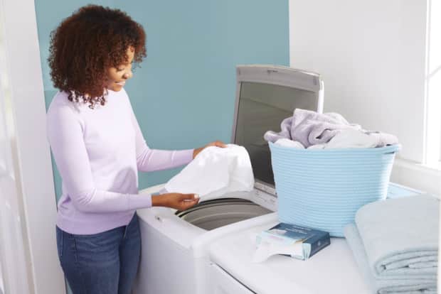 a woman washing her bed sheets in the washing machine