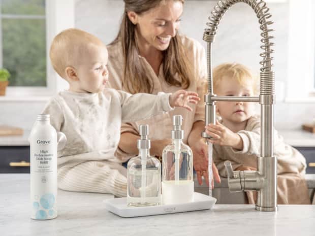Woman and two babies washing hands under faucet
