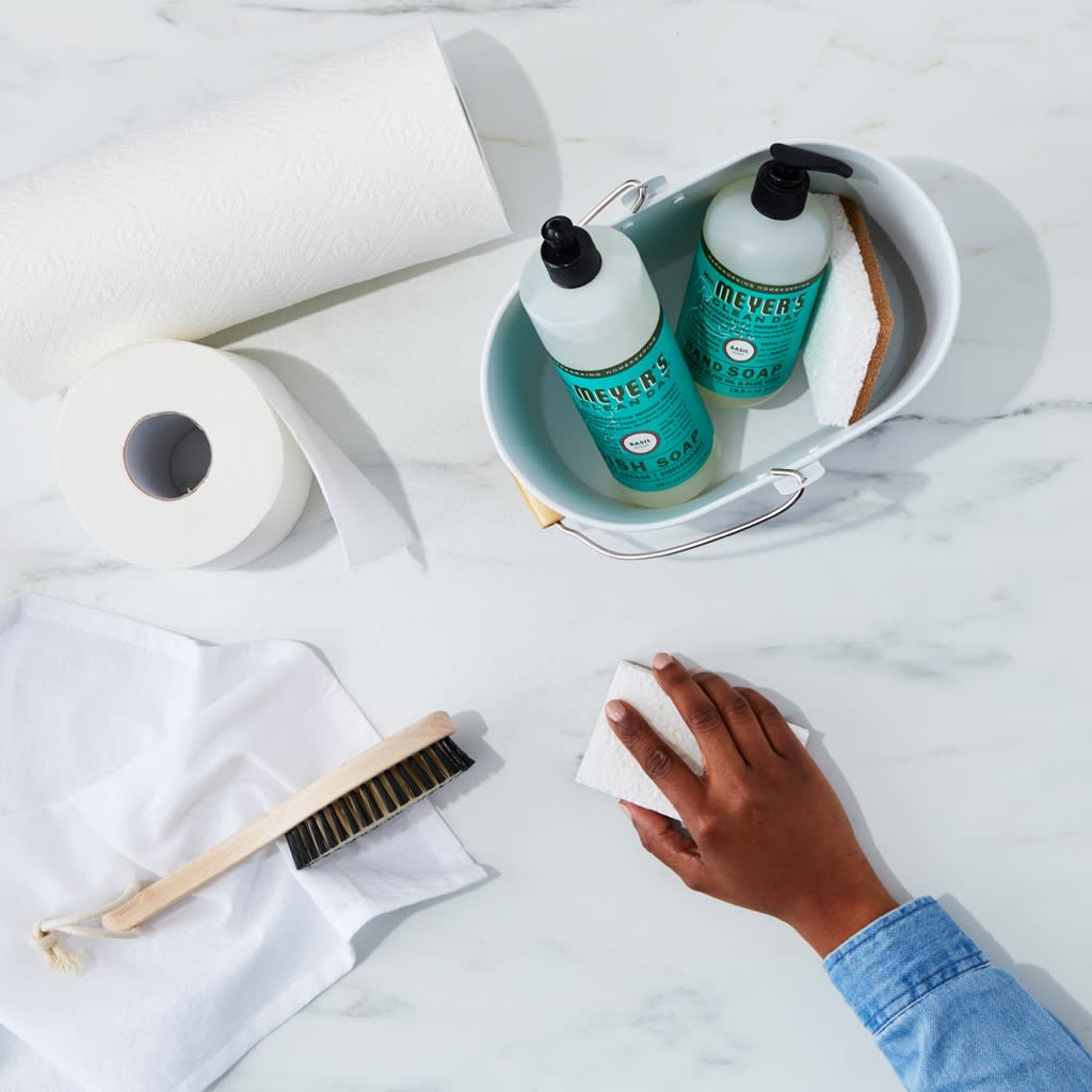 Hand wiping countertop next to cleaning supplies